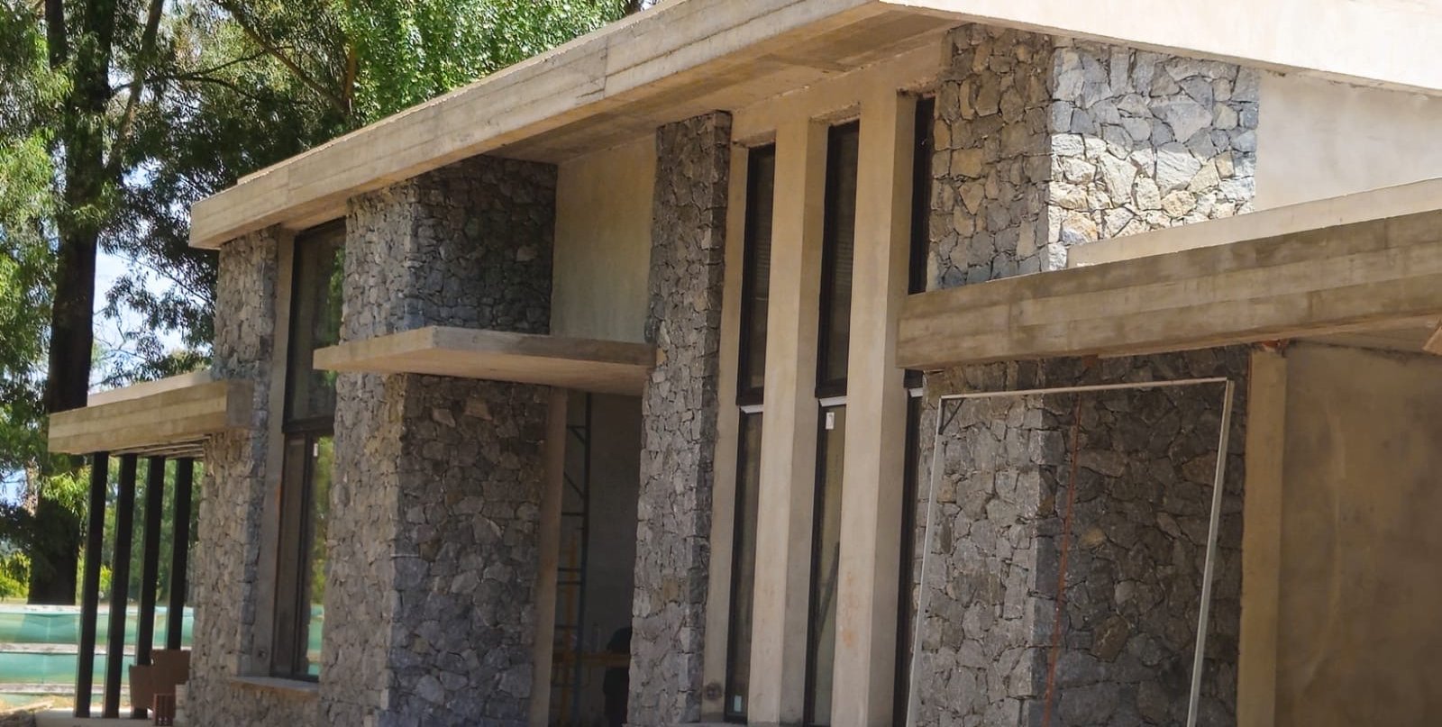 Frente de una casa con revestimiento de piedra y hormigón visto artesanal, trabajo realizado por ReveArt